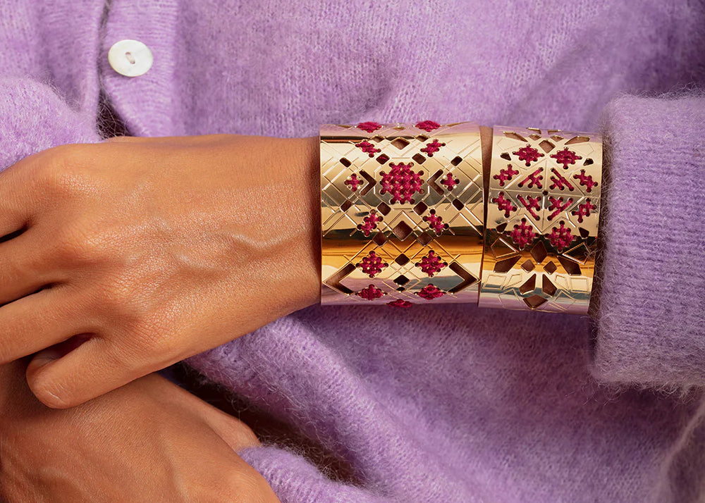 Close crop of a wrist modeling a red and gold cuff bracelet.