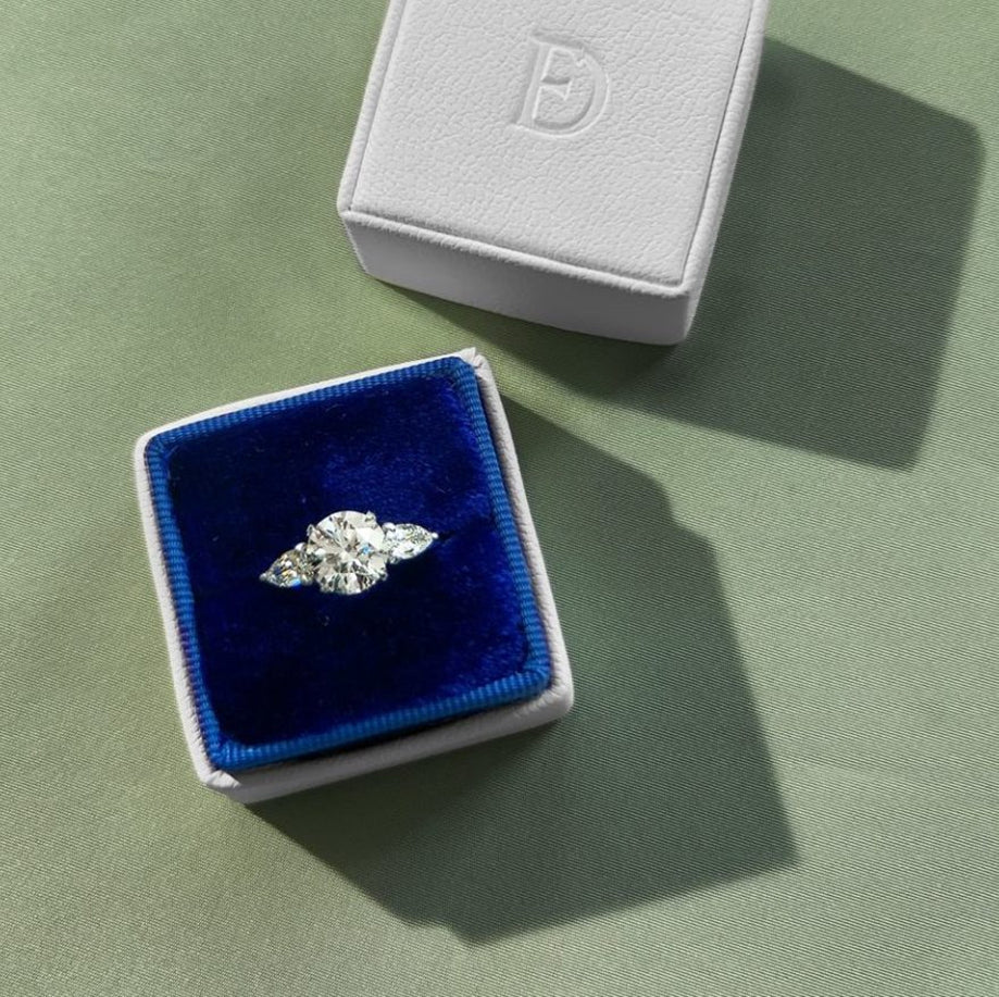 A velvet ring box showcasing a diamond ring.