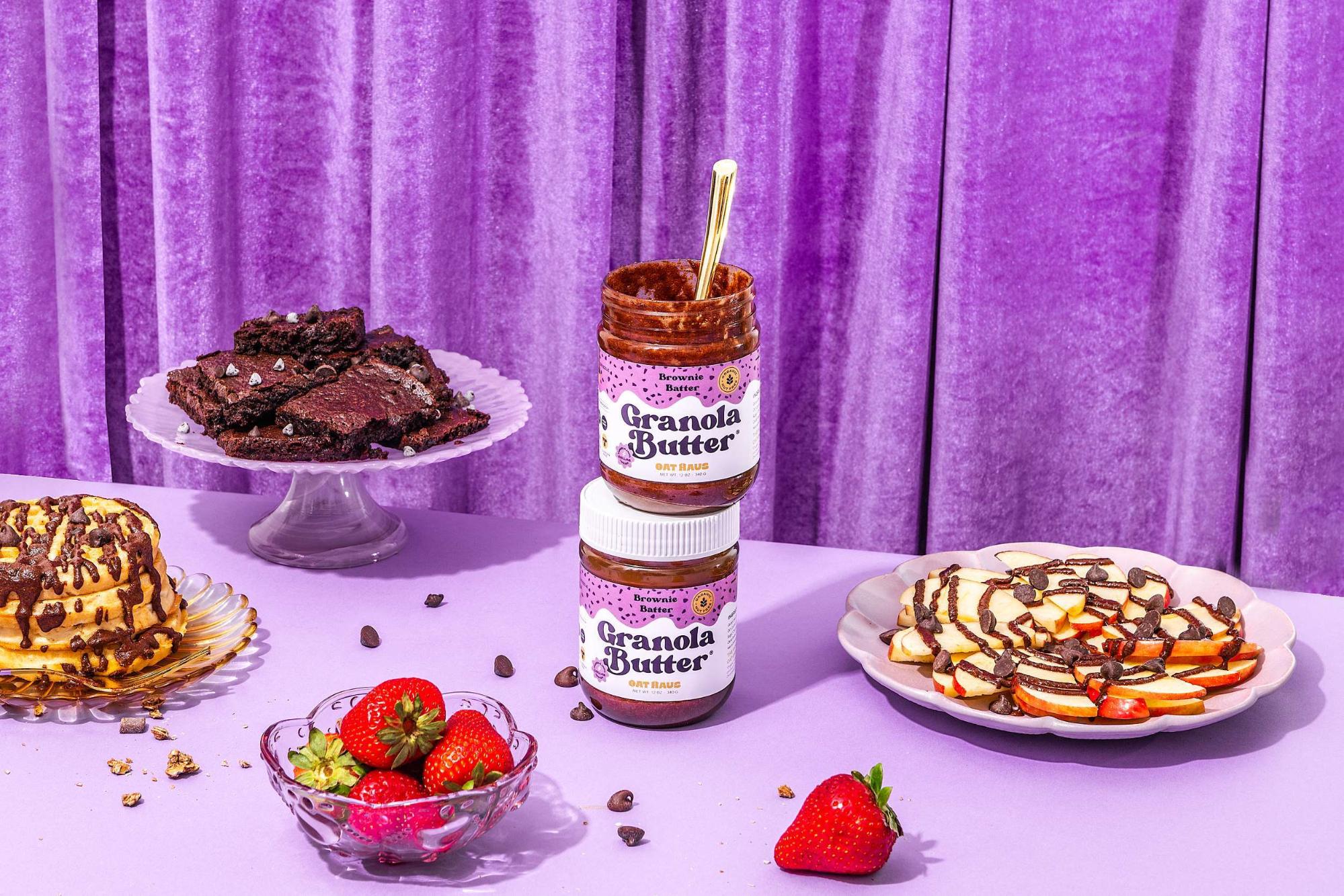 Dessert table with Granola Butter jars, strawberries, and chocolate-drizzled treats.
