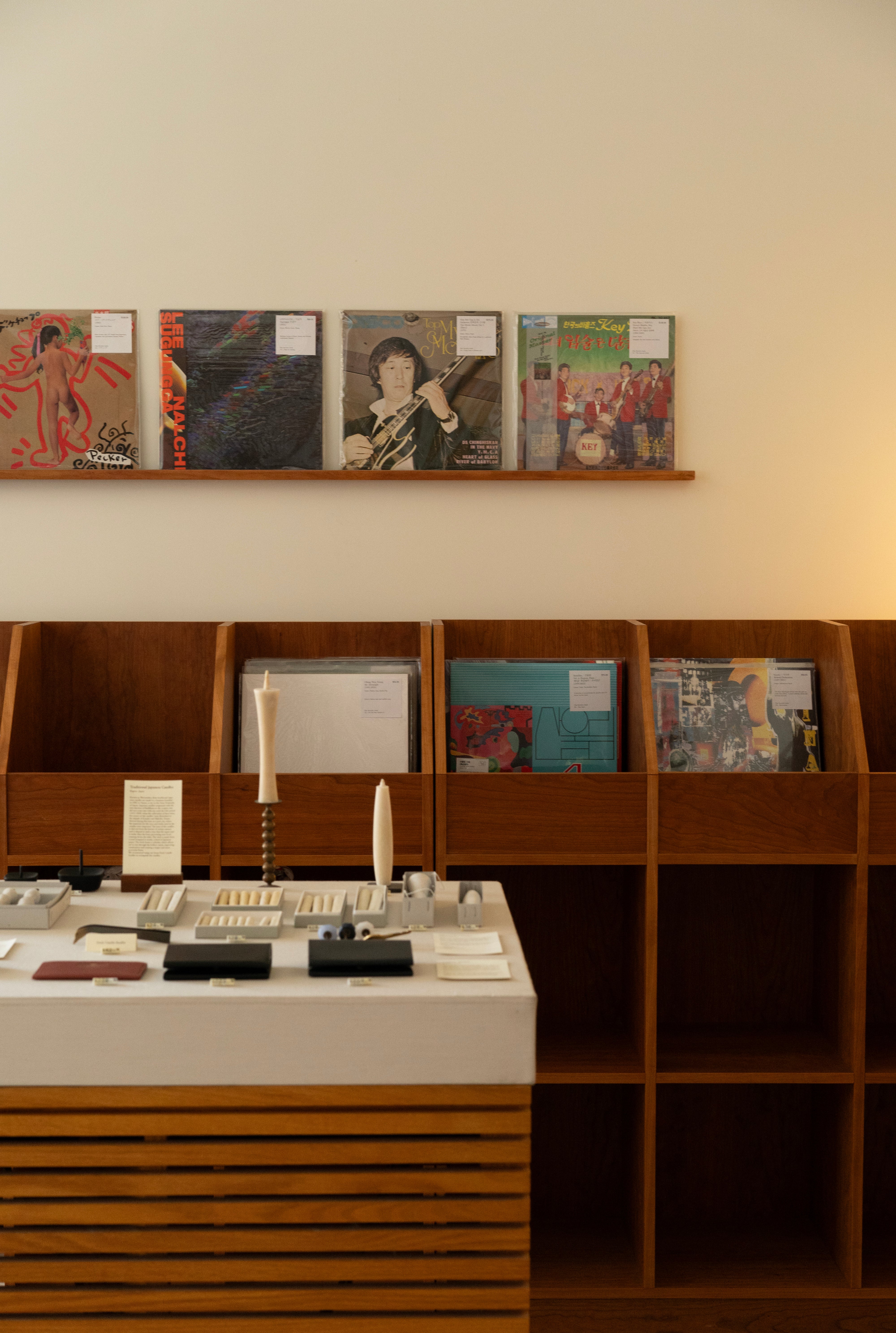 Vinyl records hang from wall in front of table holding goods
